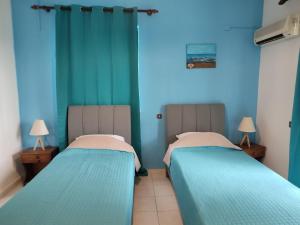 two beds in a room with blue walls at Dolphin Apartments in Faliraki