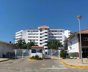 un estacionamiento frente a un gran edificio blanco en Condominio c/ alberca y vista a Marina Mazatlán, en Mazatlán