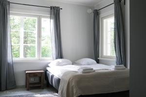 a bedroom with two beds and two windows at Gammelgård Pizza & Padel Resort in Nauvo