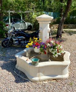 een fontein met bloemen en een motorfiets in een tuin bij La Magistrale in Lorgues