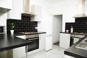 a kitchen with white cabinets and black counter tops at Easygoing Central Oasis in Liverpool