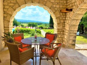 eine Terrasse mit einem Tisch, Stühlen und einem Torbogen in der Unterkunft mas des broussonnetiers in Barjac