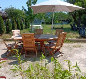 a wooden table and chairs with an umbrella at Gîte les Dames du Quint **** in Baume-les-Dames