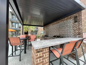 een patio met een tafel en stoelen en een bakstenen muur bij Comfy Abode near Bush Airport in Houston