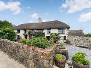 a house with a stone wall and some plants at Warmhill Farmhouse in Hennock