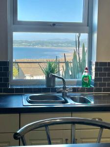 a kitchen sink and a window with a view of the ocean at Apartment 3 Benllech with Sea views in Benllech