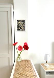 eine Vase mit roten Blumen auf einem Tisch in der Unterkunft Angels apartment in Bari