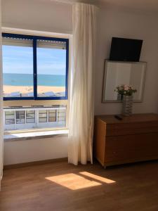 una camera con una grande finestra con vista sulla spiaggia di Apartamentos 7 Saias - Centro a Nazaré