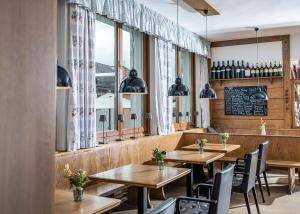 a restaurant with wooden tables and chairs and windows at MÖRWALD Relais & Châteaux Hotel am Wagram in Feuersbrunn