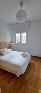 a bedroom with a large white bed with a wooden floor at Litoral beach in Málaga