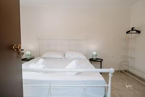 1 dormitorio con 1 cama con sábanas y almohadas blancas en Oikies Verde III-F, en Perdika