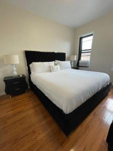 a bedroom with a large bed with white sheets and a window at 1BR Apt in Sunnyside 15 min to Manhattan in Woodside