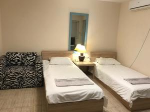 a room with two beds and a table with a lamp at Ssenyange Guest House in Varna City