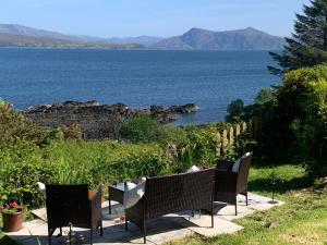 a row of chairs sitting next to a body of water at Tighnamara-Skye in Saasaig