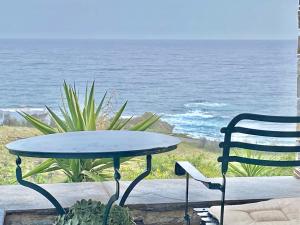 a table and a chair sitting next to the ocean at Vigla Stone House in Karistos