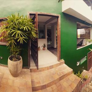 una casa verde con una pared verde y plantas en Meu Dengo Pousada, en Morro de São Paulo