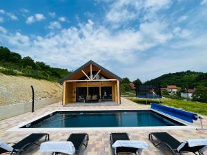 a swimming pool with chairs and a house at Holiday House Novus in Selno