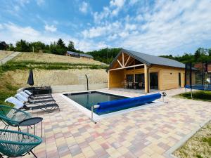 a pool in a patio with chairs and a house at Holiday House Novus in Selno