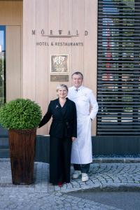 a man and a woman standing in front of a building at MÖRWALD Relais & Châteaux Hotel am Wagram in Feuersbrunn