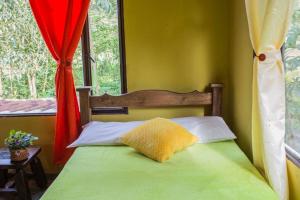 a bedroom with a bed with a yellow pillow on it at Cabaña Mikhuna, Bienestar en las montañas !!! in Anolaima