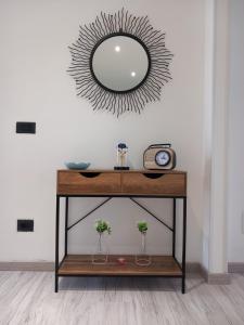 uma mesa com um espelho e um relógio na parede em La Rosa BLUtique Guesthouse - Boutique apartment near Como em Lucino