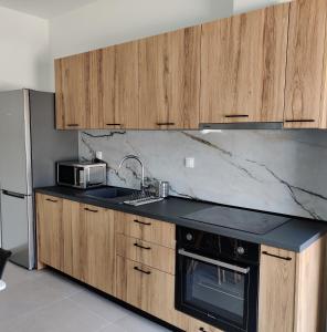 a kitchen with wooden cabinets and a sink and a microwave at Mare Monte Luxury Apartments 4 in Kassandria