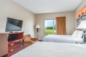 a hotel room with two beds and a flat screen tv at Days Inn by Wyndham Coliseum Montgomery AL in Montgomery