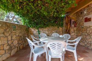 een tafel en stoelen voor een stenen muur bij Apartamentos Mayans in Sant Ferran de Ses Roques