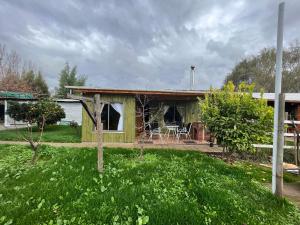 a green house with a table and chairs in a yard at Alojamiento Machicura in Linares