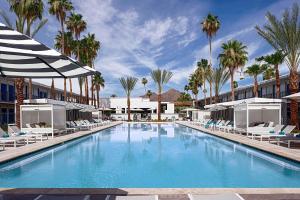 a large swimming pool with chairs and palm trees at Hotel Adeline, Scottsdale, a Tribute Portfolio Hotel in Scottsdale