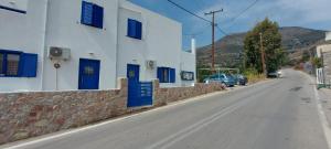 eine leere Straße neben einem weißen Gebäude mit blauen Fensterläden in der Unterkunft Dionysia apartments in Livadia
