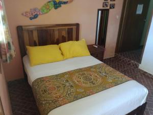 1 cama con 2 almohadas amarillas en una habitación en CANCUN GUEST HOUSE, en Cancún