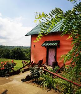 uma pequena casa vermelha com um telhado verde em Sunny Side Fruska Gora -touristic estate em Velika Remeta