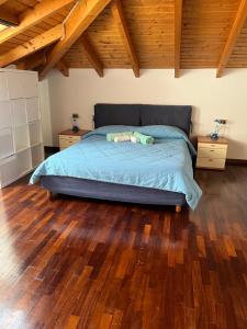 a bedroom with a bed with a wooden floor at Appartamento MANUELA in Consiglio di Rumo