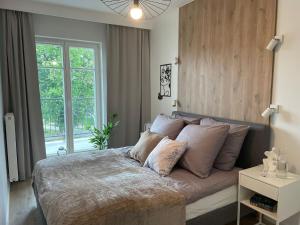 Un dormitorio con una cama grande y una ventana en Apartament Kameralis Old Town - klimatyzacja - balkon - winda, en Elbląg