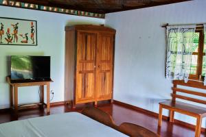 a bedroom with a television and a wooden cabinet at Villa MILENA in Nosy Be