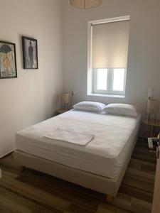 uma cama branca num quarto com uma janela em Alani house em Tinos