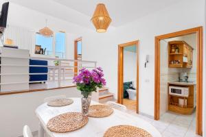 プエルト・デ・サンティアゴにあるPanomaric Sea View - Sol Apartmentのキッチン、ダイニングルーム(紫の花のテーブル付)