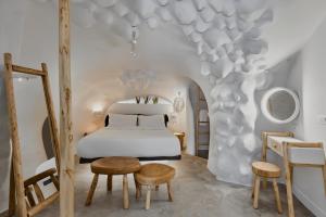 een slaapkamer met een bed en 2 stoelen en een tafel bij Theano Cave Suites & Villas in Imerovígli