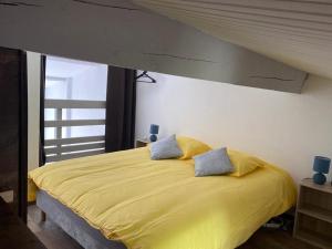 1 dormitorio con 1 cama amarilla grande y 2 almohadas en Location vacance vue mer 4 à 6 personnes, en Cavalaire-sur-Mer