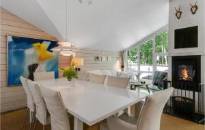 een eetkamer met een witte tafel en stoelen en een open haard bij Lovely Home In Rnde With Kitchen in Rønde