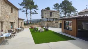 eine Terrasse mit Tischen und Stühlen auf einer grünen Wiese in der Unterkunft A Casa de Elisa in Laxe