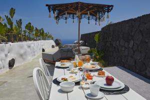 un tavolo con piatti di cibo e un ombrello di Theano Cave Suites & Villas a Imerovigli