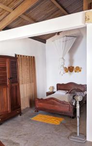 a bedroom with a bed and a desk and a fan at Hôtel chez Pat in Nosy Be