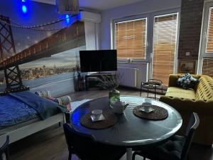 a living room with a table and a bed at Apartament Awiator Gdańsk in Gdańsk