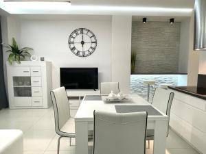 a dining room with a table and a clock on the wall at I&M Apartments Sikorskiego Wrocław in Wrocław
