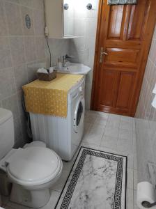a bathroom with a toilet and a sink and a washing machine at Angelic House in Spetses