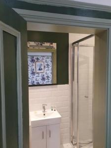 a bathroom with a white sink and a shower at The Lodge Stanwell in Stanwell