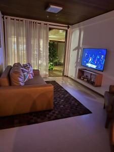 sala de estar con sofá y TV de pantalla plana en Villa Andorinha, Apt 03, en Mucugê
