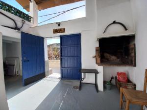 Habitación con puerta azul, mesa y silla en Casa Cueva EL PORTÓN, en Alcalá del Júcar